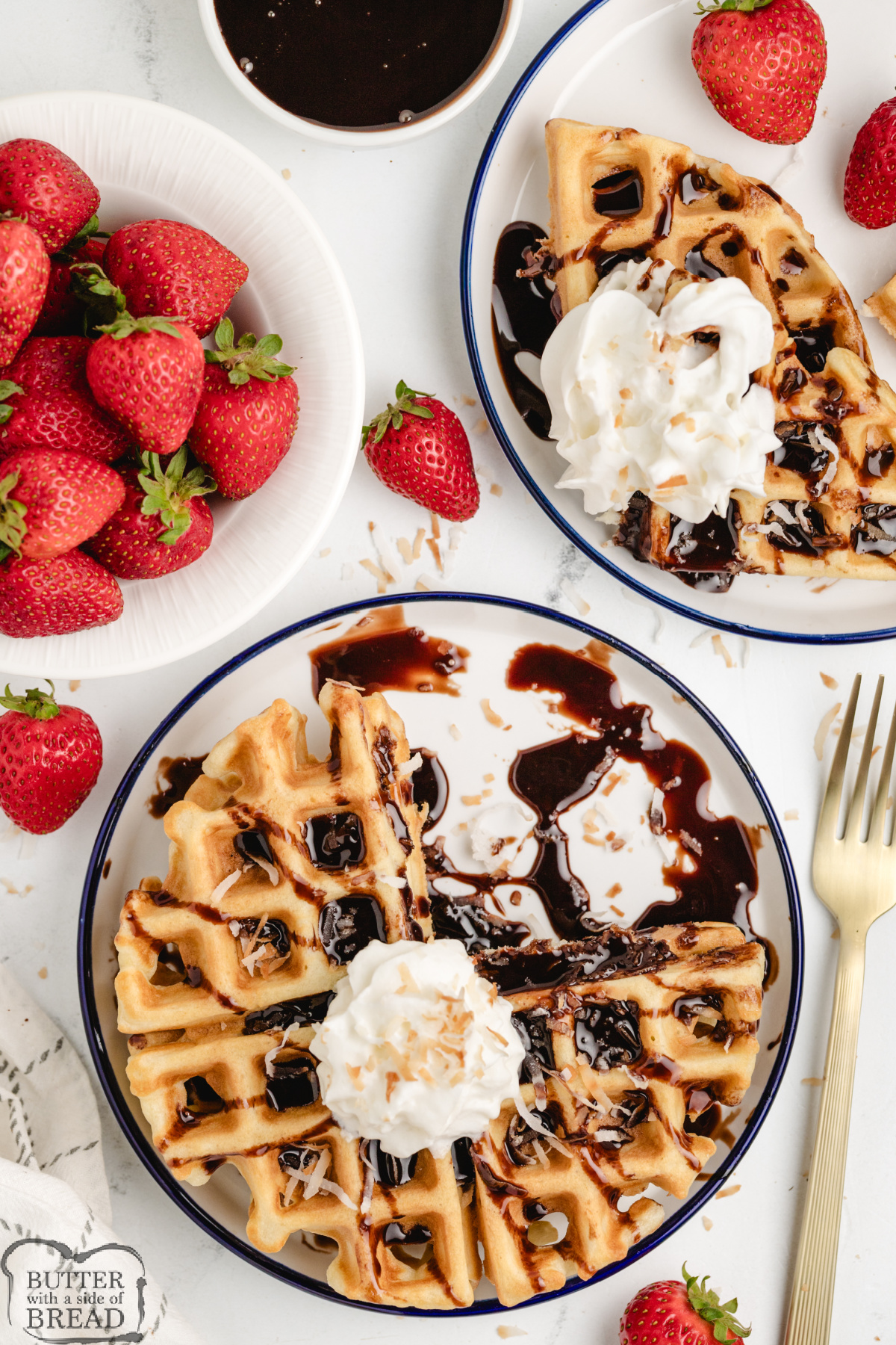 Fluffy coconut waffles topped with whipped cream and a drizzle of chocolate syrup.