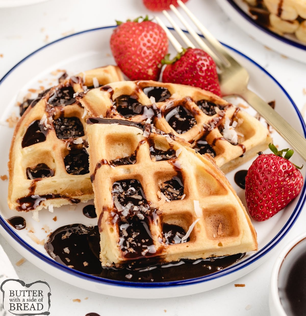 Coconut waffles on a white plate with whipped cream and chocolate syrup.