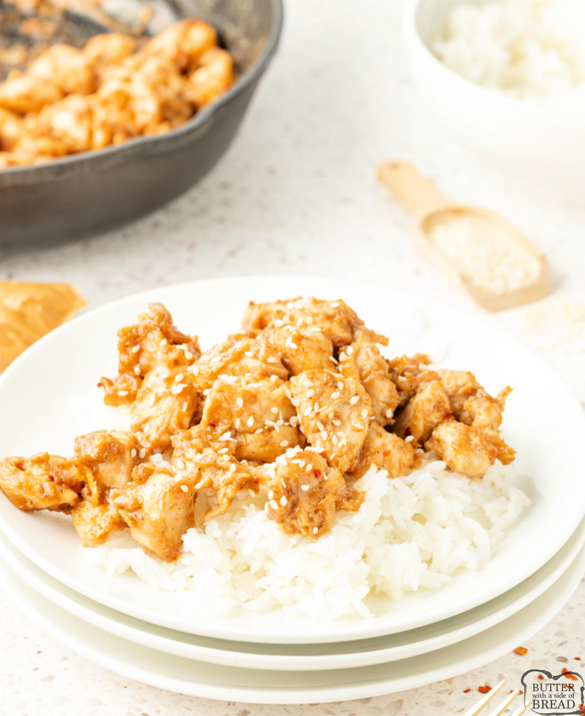 Peanut butter chicken served over white rice and topped with sesame seeds.