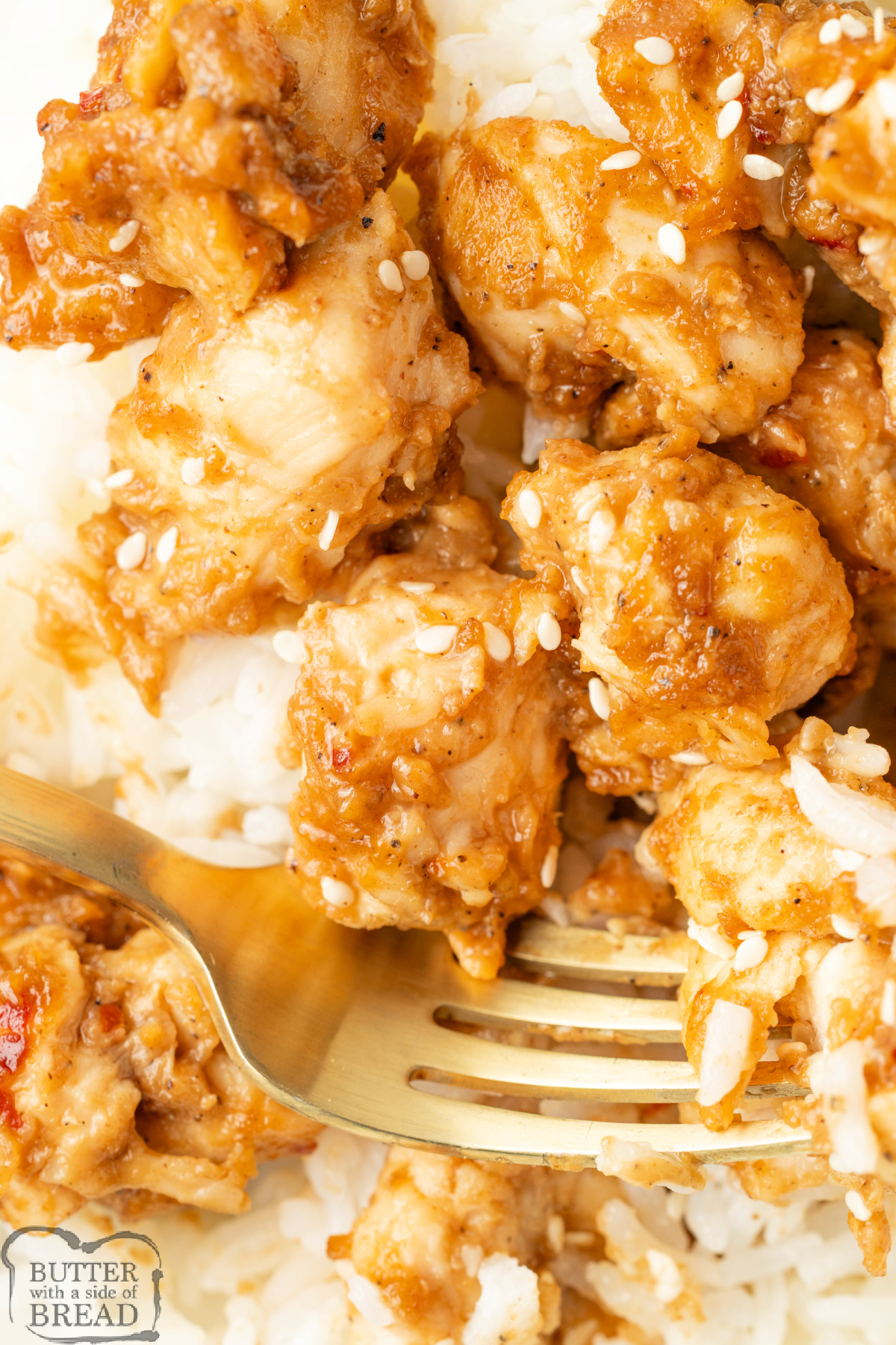 Closeup of peanut butter chicken over rice topped with sesame seeds.