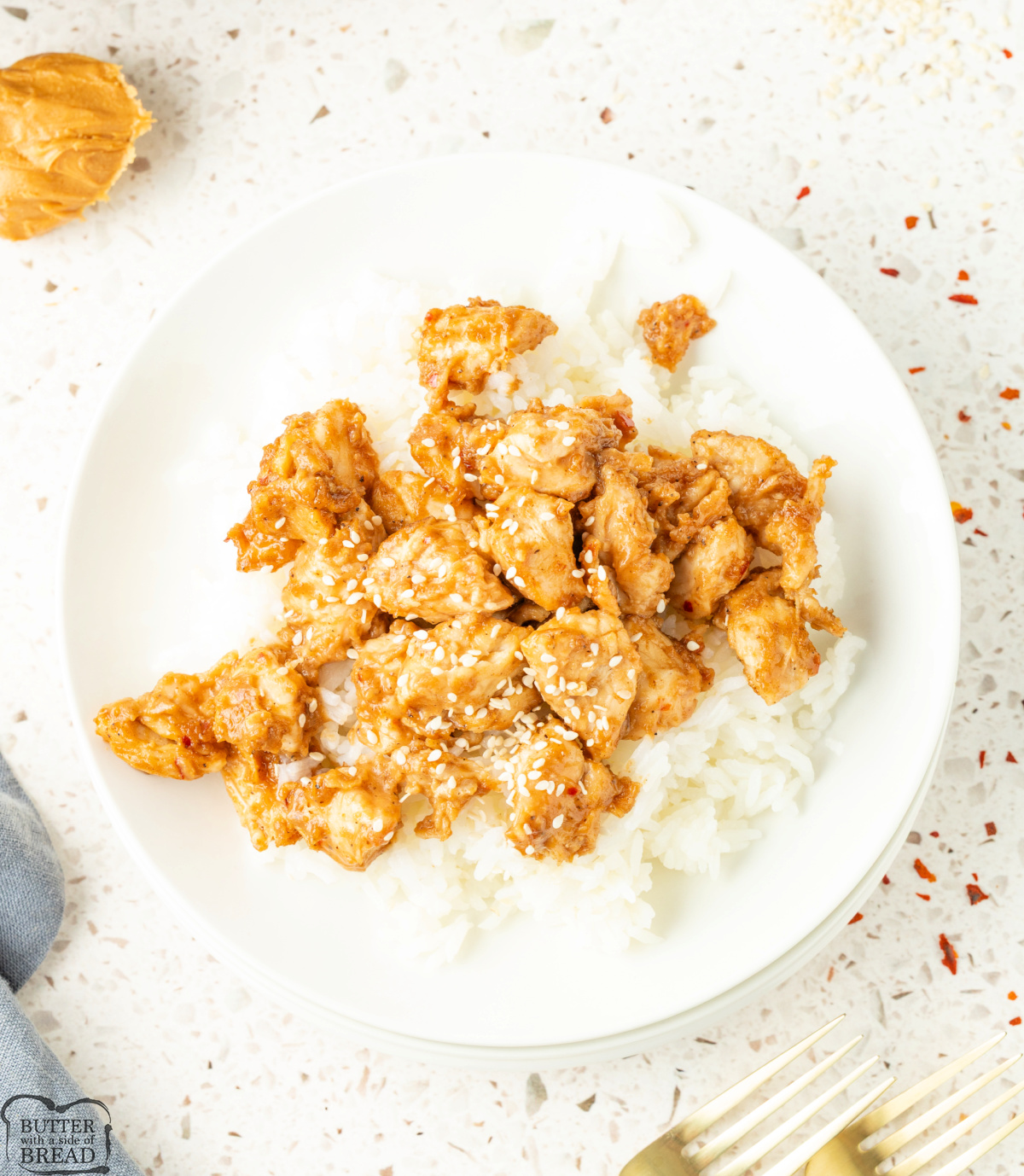 Tender chicken pieces coated in a creamy peanut butter and hoisin sauce, served over fluffy white rice and garnished with sesame seeds.