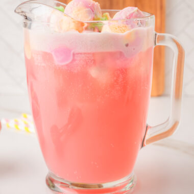 Rainbow Sherbet Punch in a glass pitcher topped with scoops of rainbow sherbet
