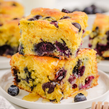 two pieces of blueberry cornbread stacked on a white plate