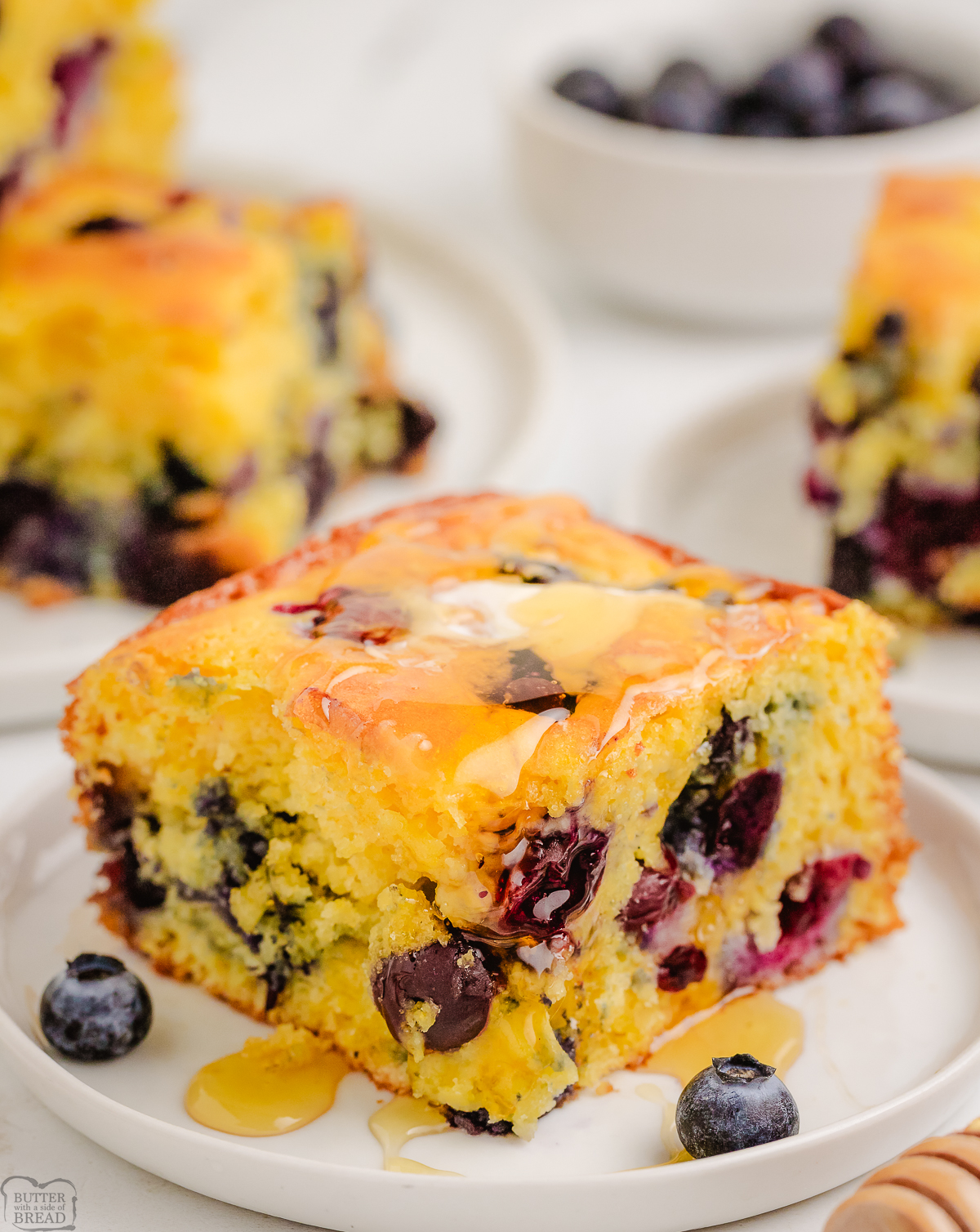 blueberry cornbread topped with honey on a white plate