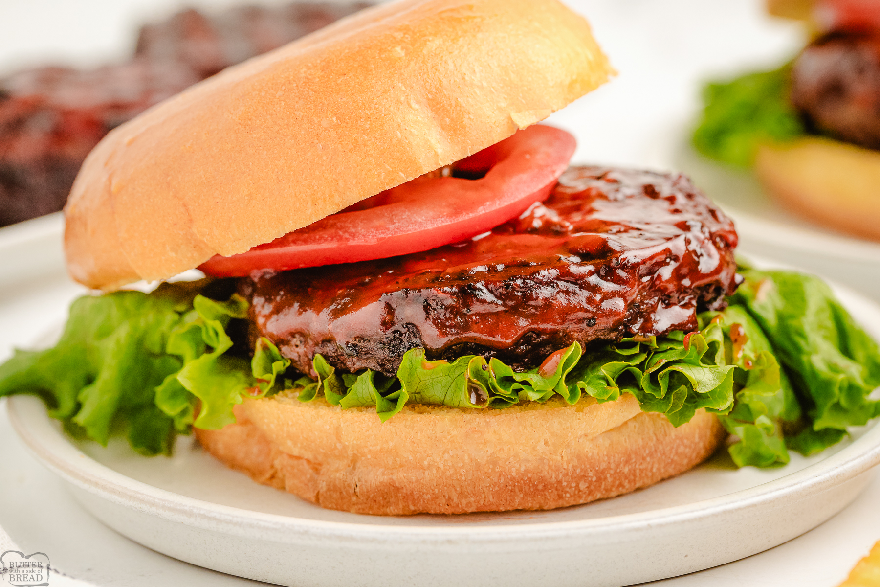 homemade hamburgers made with a Coca Cola glaze on a white plate with lettuce and tomato