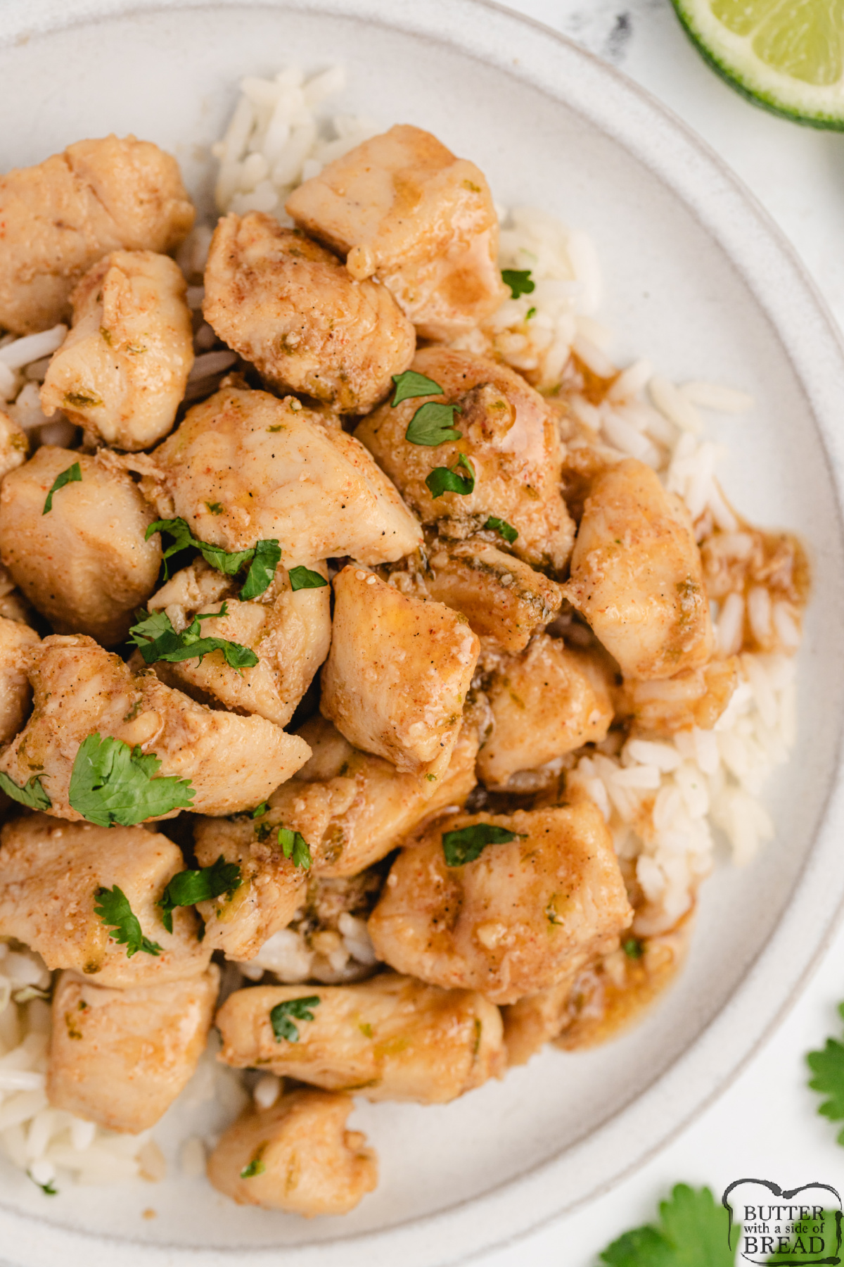 Overhead view of honey lime chicken skillet over white rice with lime wedges and fresh cilantro.