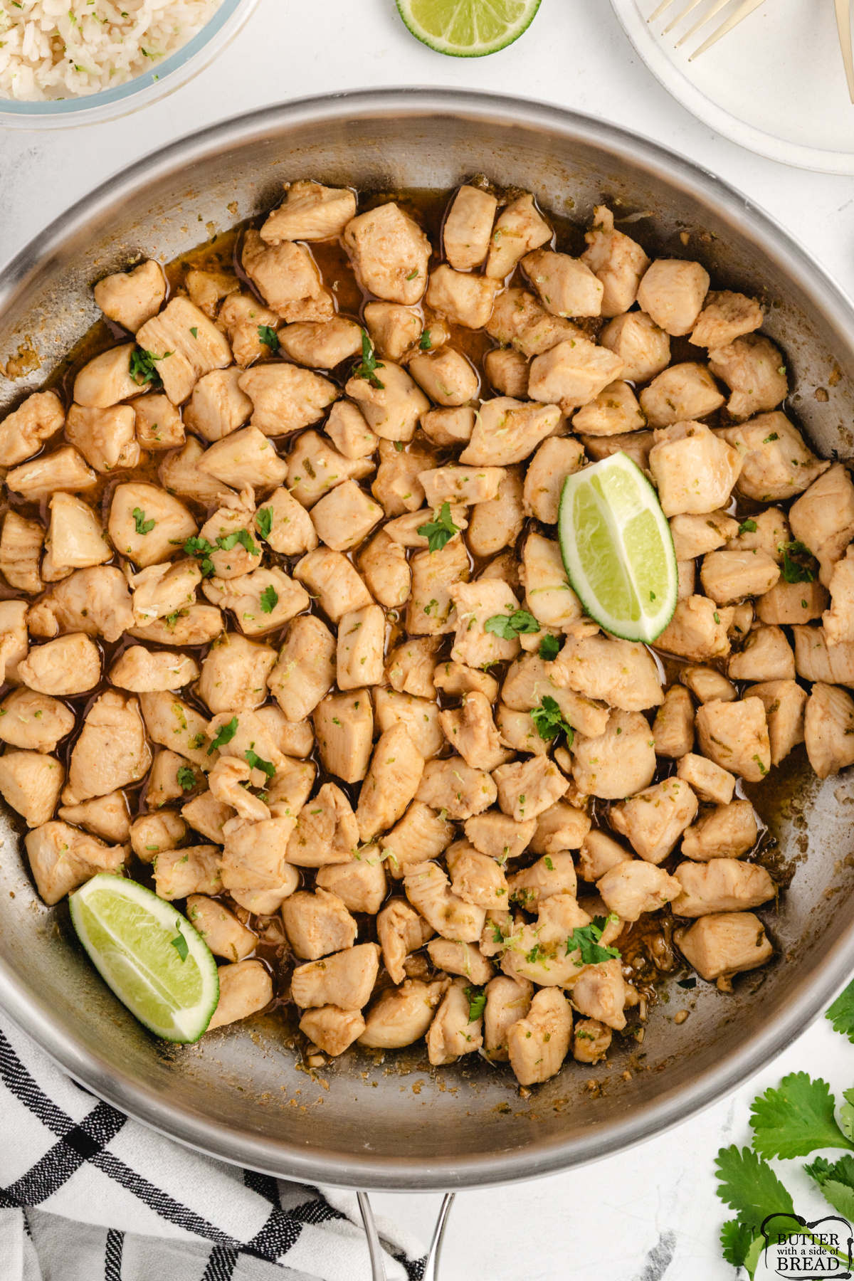 A skillet of honey lime glazed chicken pieces garnished with fresh cilantro and lime wedges.