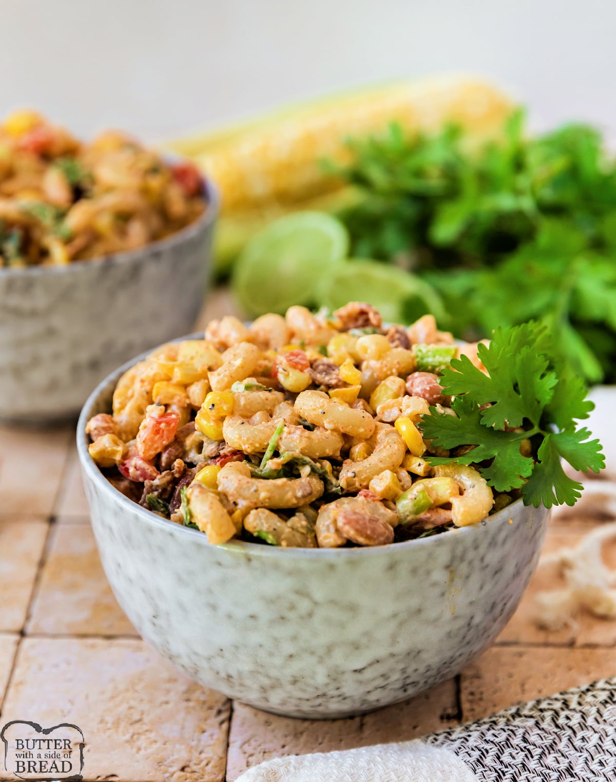 Creamy Mexican street corn pasta salad garnished with cilantro and cotija cheese in a white serving bowl.