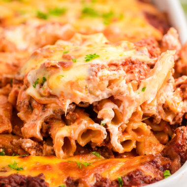 scooping out a serving of baked ziti from a baking dish