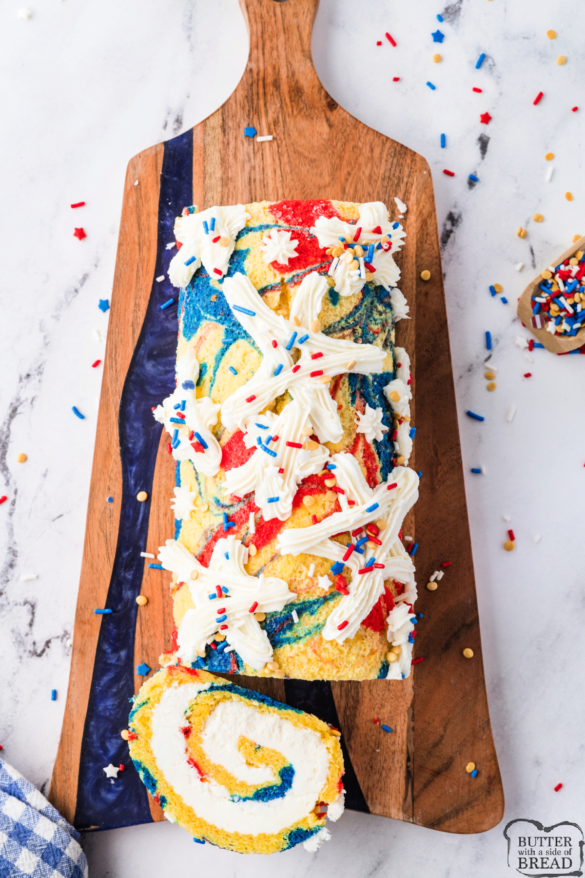 Patriotic cake roll on a wooden board with red white and blue sprinkles on top.