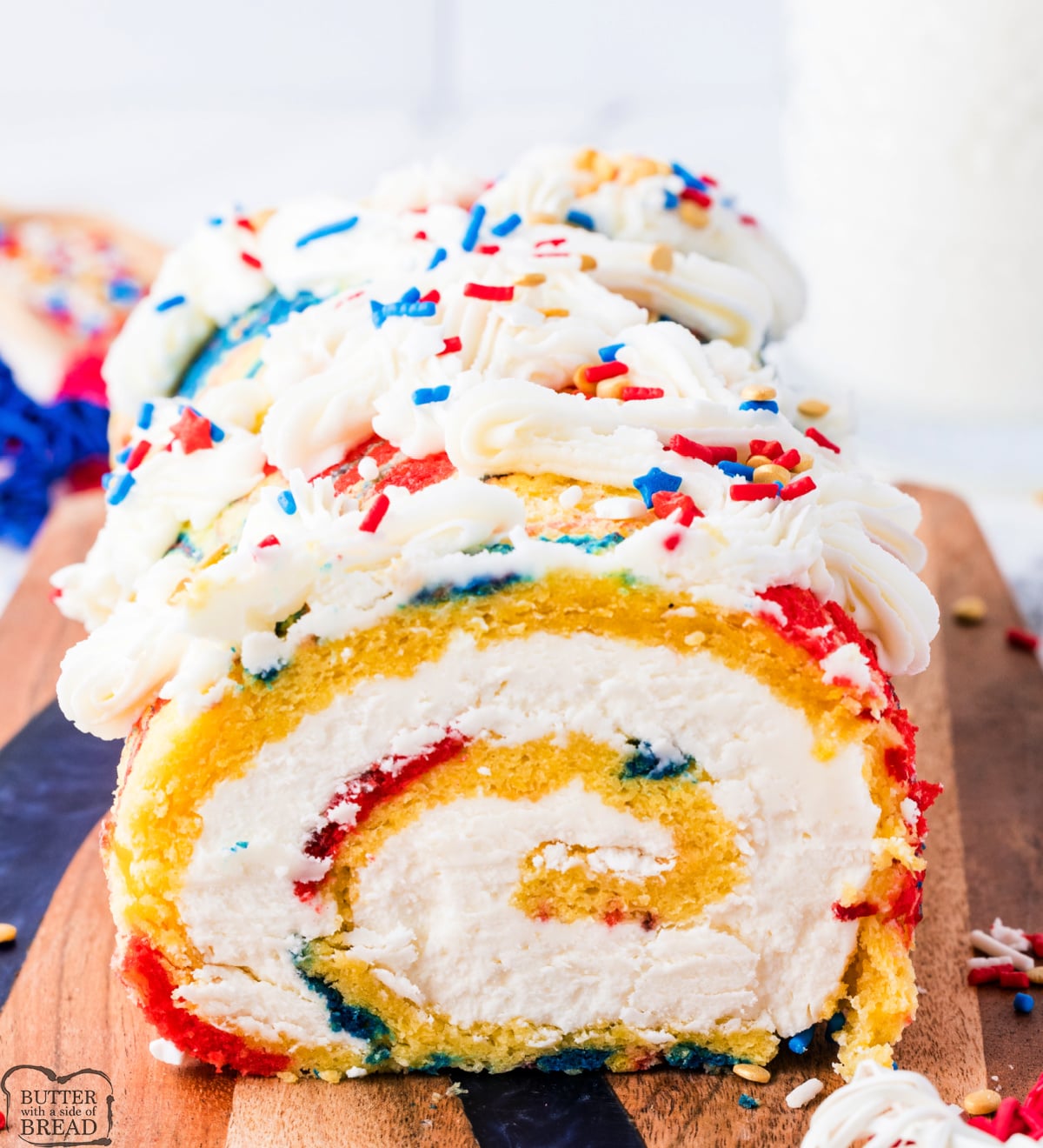 Close-up of a patriotic cake roll slice showing the colorful swirled sponge cake and fluffy buttercream.