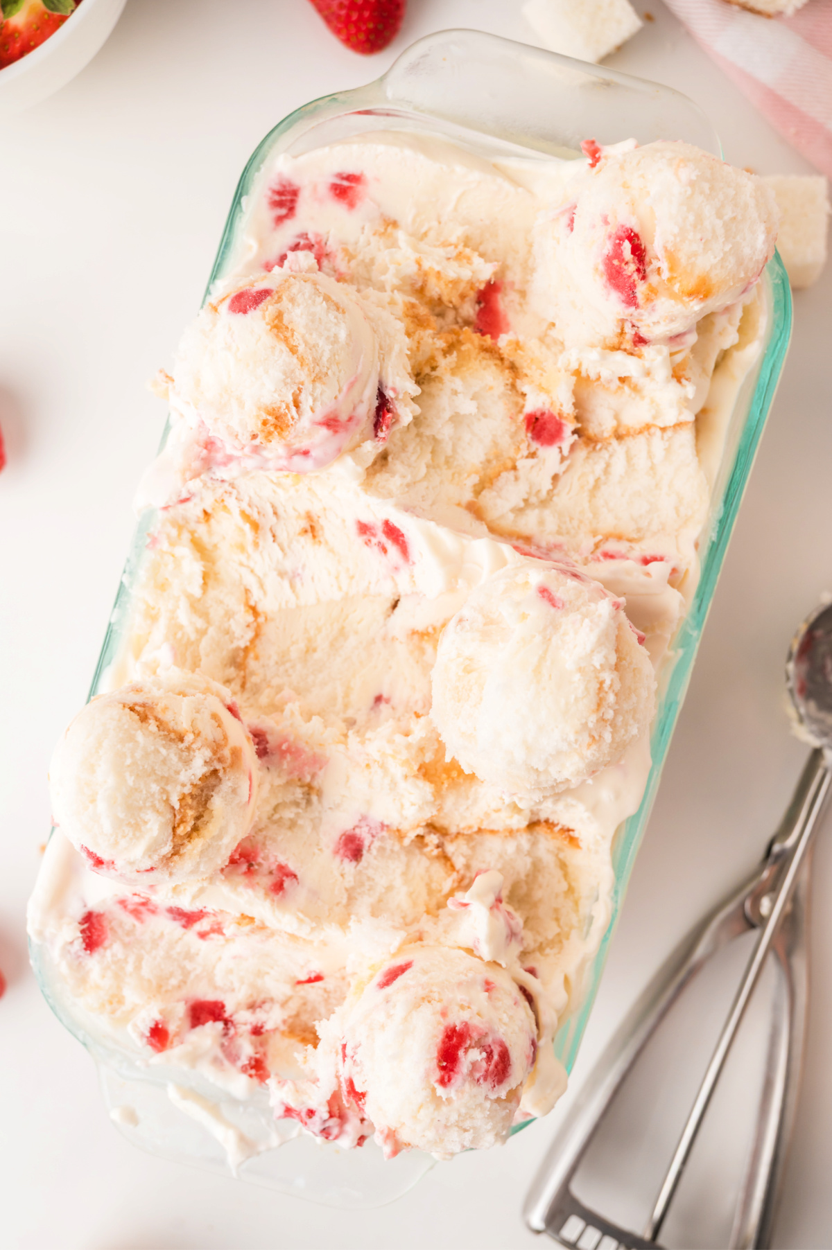 Scoops of creamy strawberry shortcake ice cream with swirls of strawberry sauce.