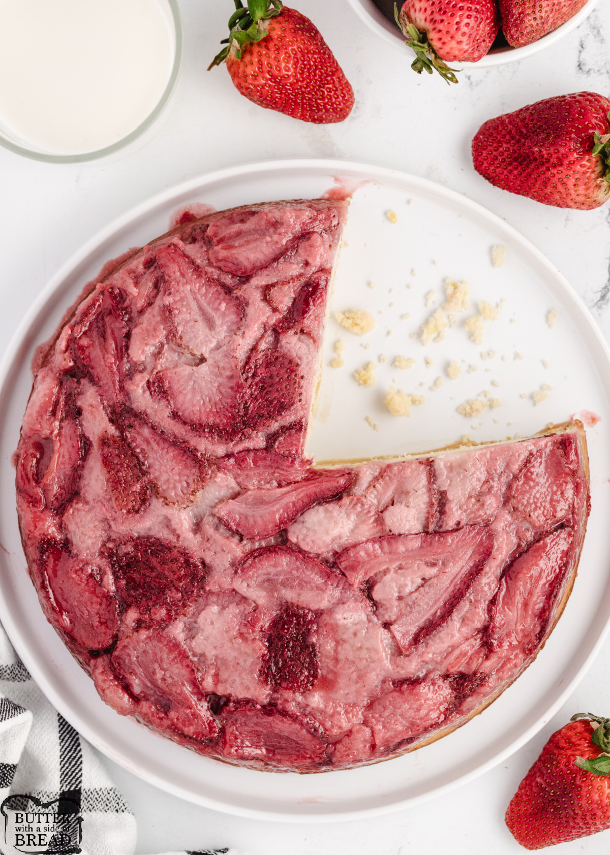 Overhead view of a whole strawberry upside-down cake with ruby red strawberry slices arranged across the top.