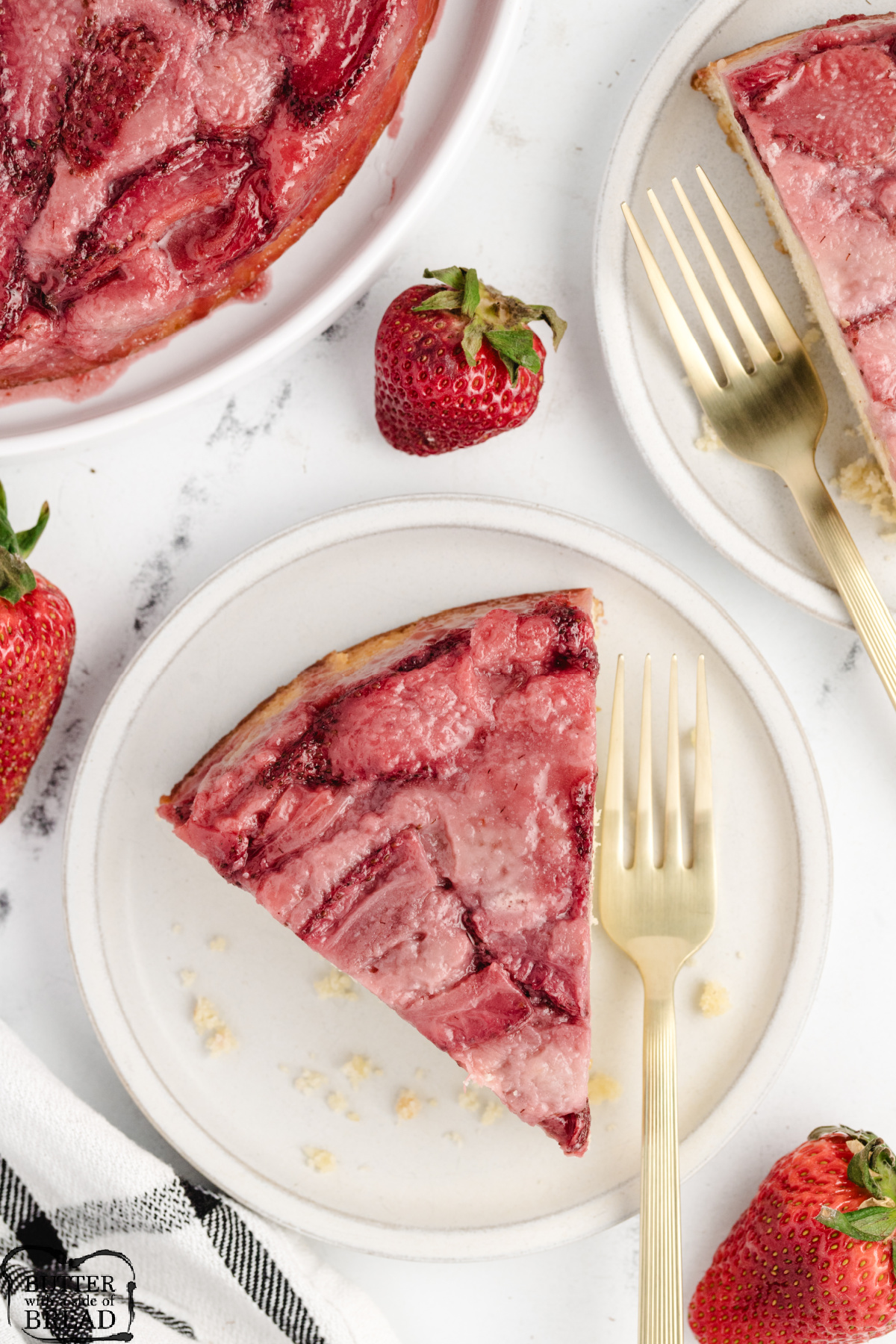 A slice of strawberry upside-down cake on a fork showing layers of fruit and tender lemon zest cake.