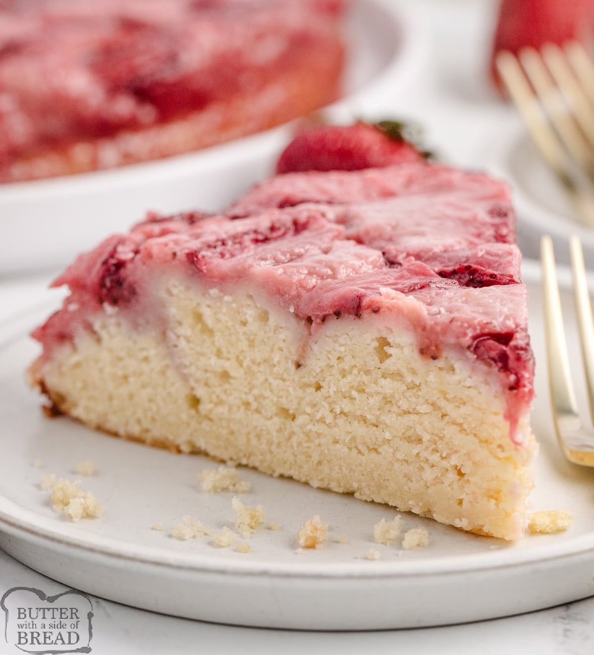 Slice of strawberry upside-down cake on a plate showing soft buttery crumb and caramelized strawberry topping.