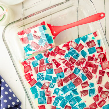 slicing a square of broken glass jello in red, white and blue colors