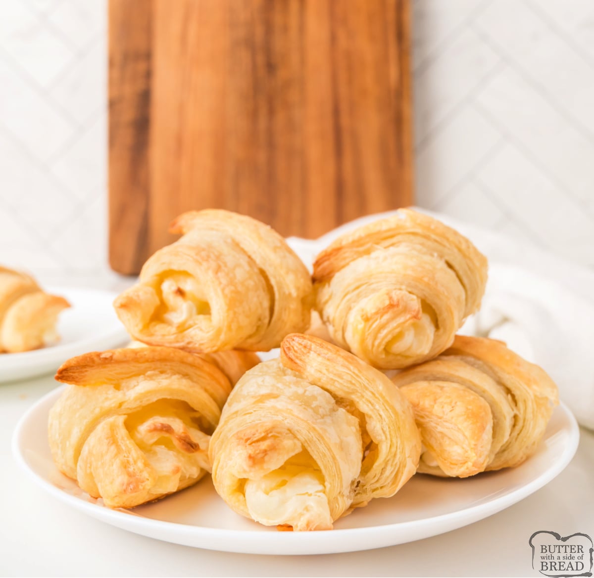 Cream cheese croissants stacked on a serving platter.