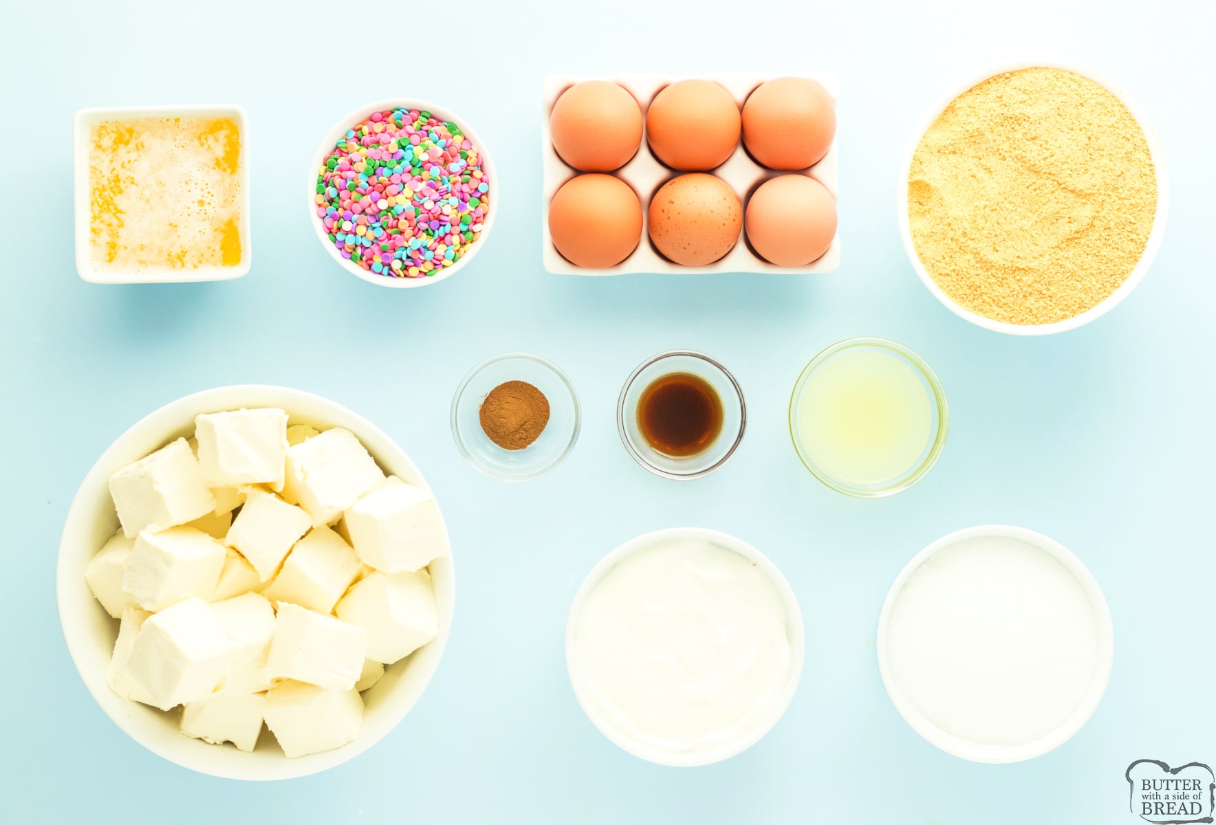 Ingredients for funfetti cheesecake including cream cheese, sprinkles, and graham crackers