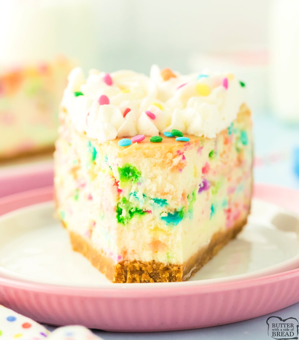Slice of funfetti cheesecake showing rainbow sprinkles throughout.