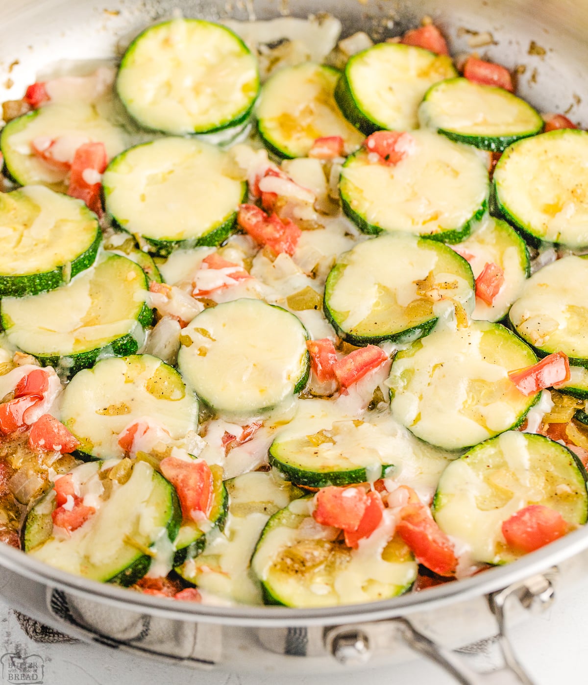 sauteed zucchini and green chiles in a skillet with tomatoes and Jack cheese