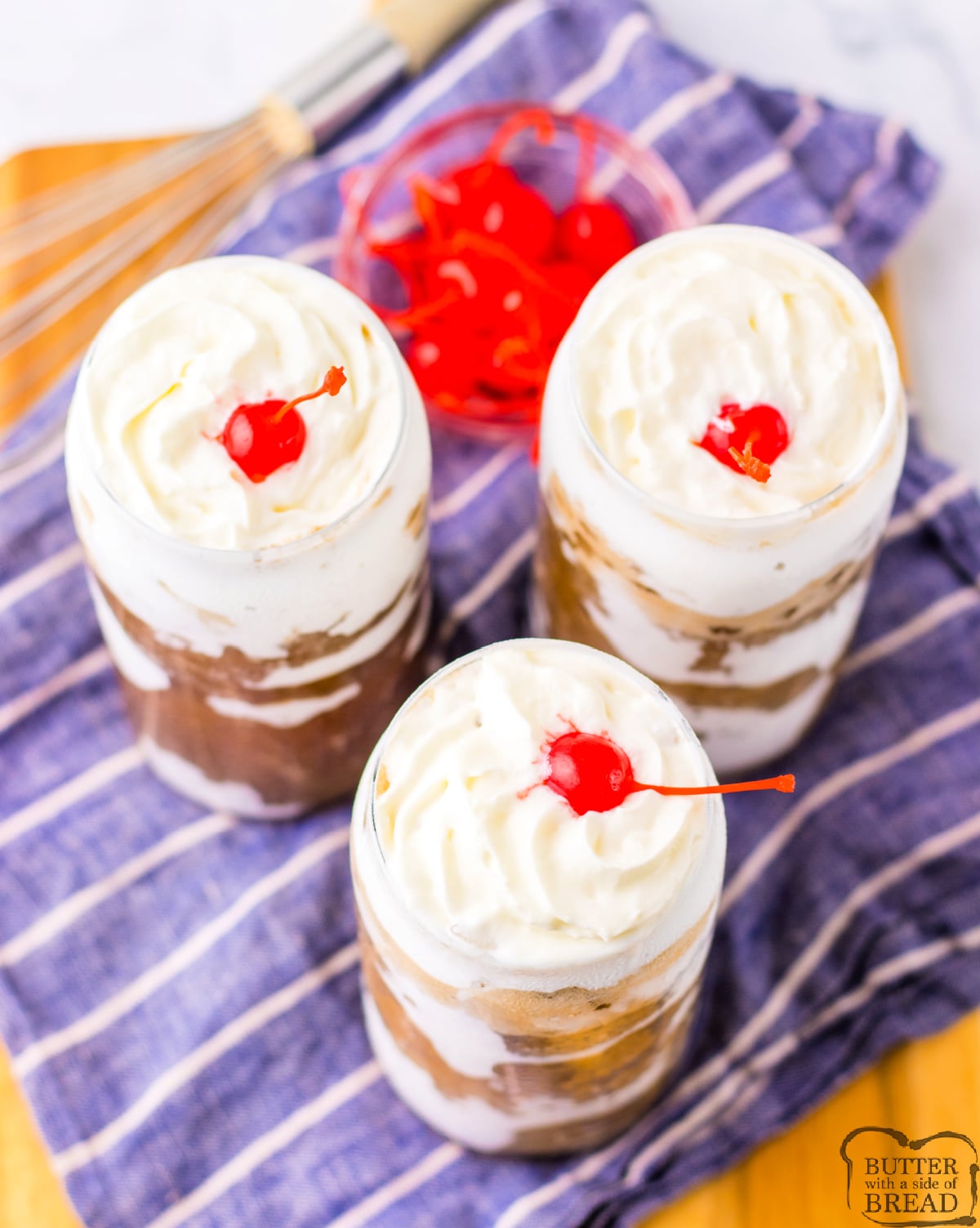 Fluffy Coke recipe with marshmallow fluff coating the glass, topped with whipped cream and a cherry