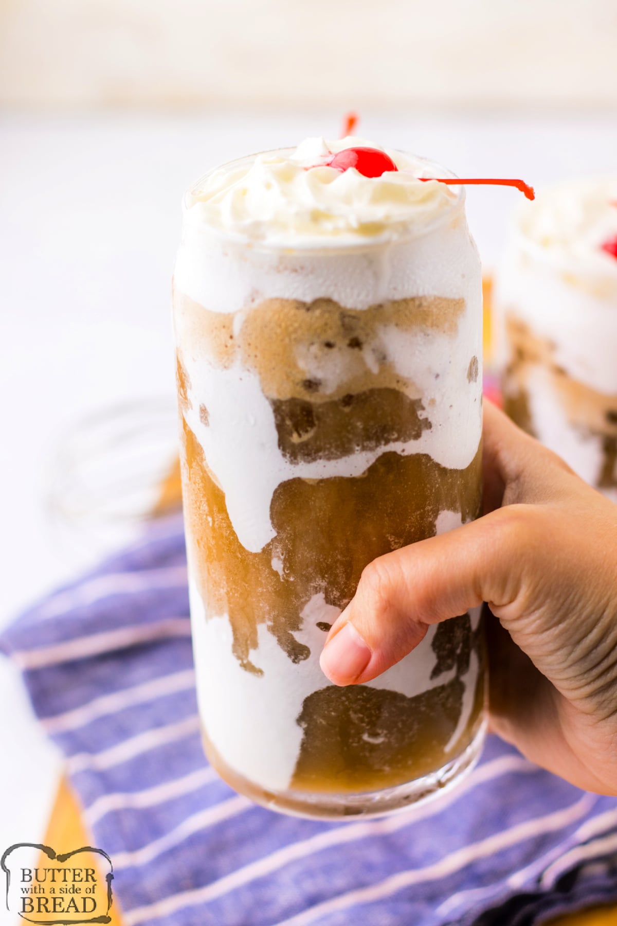 Tall glass of viral Fluffy Coke with nugget ice, whipped cream and a cherry on top