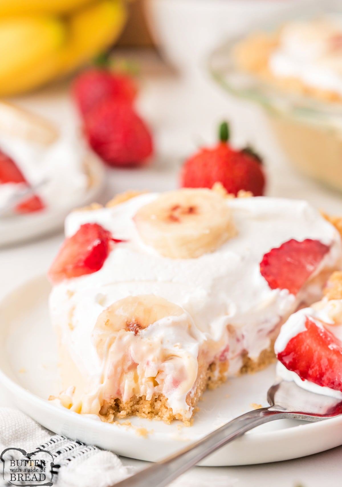 A single slice of no bake strawberry banana pie on a white plate showing the vanilla wafer crust, creamy pudding filling, and fresh fruit layers.