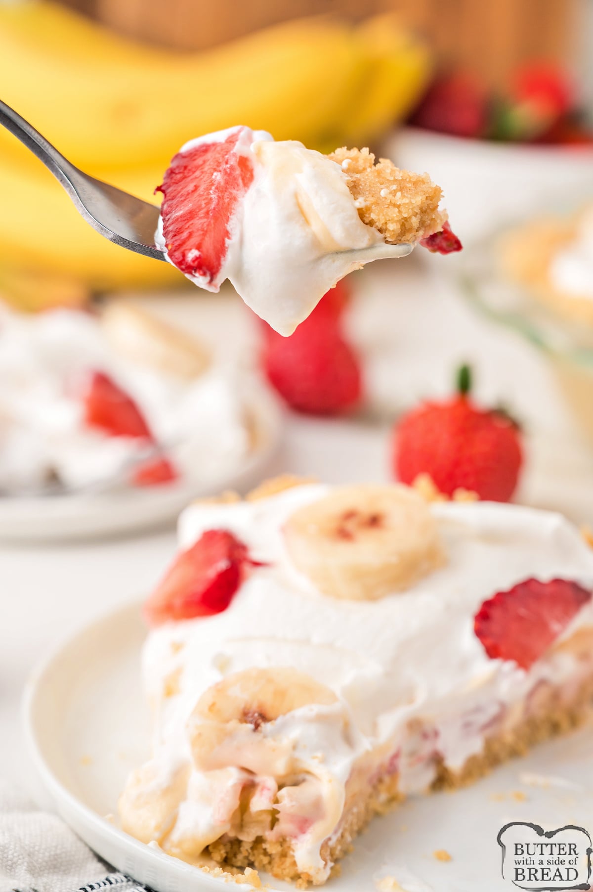 Close-up of no bake strawberry banana pie topping showing sliced strawberries and banana rounds on a bed of whipped cream.
